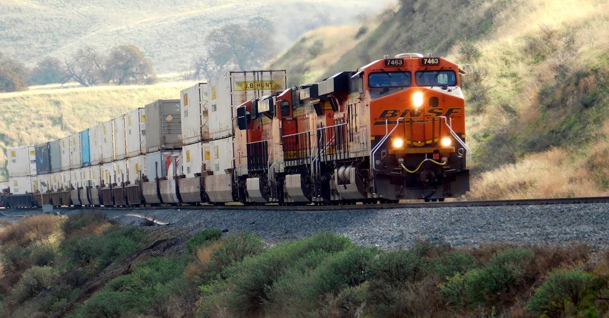 Freight train passing through scenic hills with vibrant landscape.